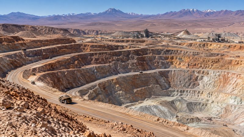 Open-pit copper mine in Chile's Atacama Desert, with terraced rock and haul trucks